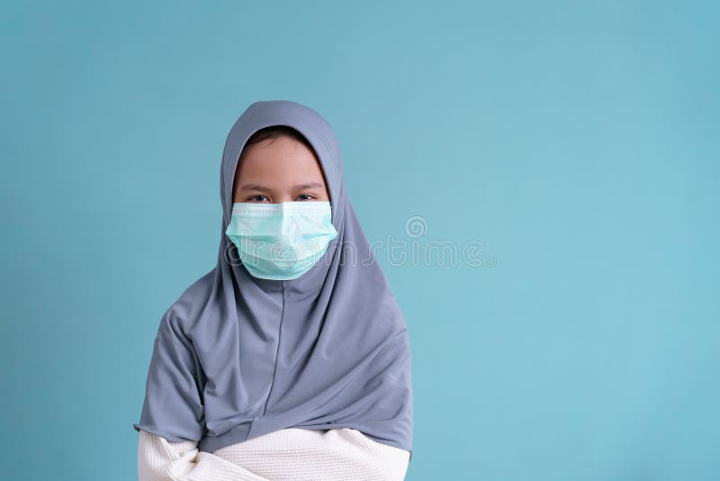Muslim little girl wearing a protection mask epidemic of flu or COVID-19 on blue background isolated. stock images Muslim little girl wearing a protection mask epidemic of flu or COVID-19 on blue background isolated. stock images