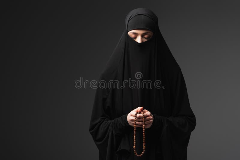 Muslim woman in black niqab praying