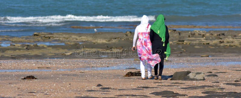 Muslim women. AUCKLAND, NZL - JAN 25 2015:Two muslim women on the beach.Over 130 million women and girls have experienced Female genital mutilation, 21% of stock images Muslim women. AUCKLAND, NZL - JAN 25 2015:Two muslim women on the beach.Over 130 million women and girls have experienced Female genital mutilation, 21% of stock images