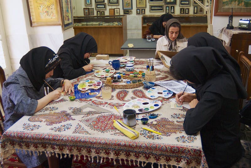 Muslimska kvinnakonstnärer i svarta headscarfs målar den traditionella persiska miniatyren i ett seminarium i Isfahan, Iran royaltyfri foto Muslimska kvinnakonstnärer i svarta headscarfs målar den traditionella persiska miniatyren i ett seminarium i Isfahan, Iran royaltyfri foto