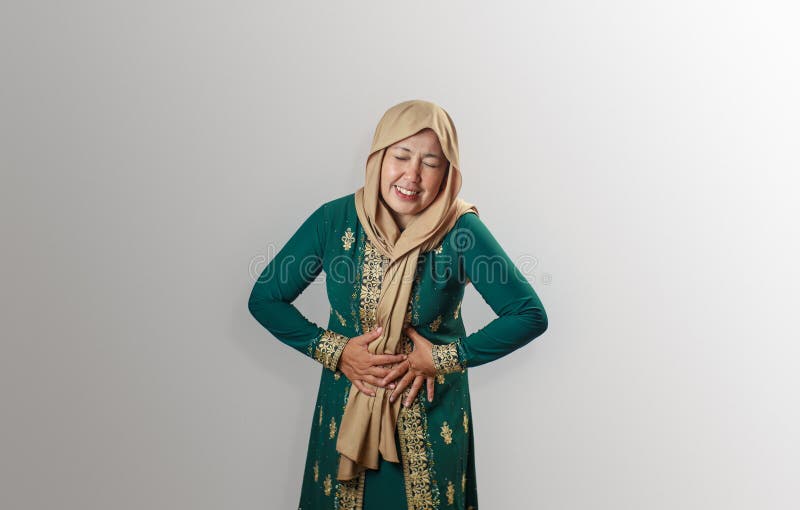 Muslimska kvinnor i traditionell press som uttrycker obehag från stomaksmärta royaltyfria bilder