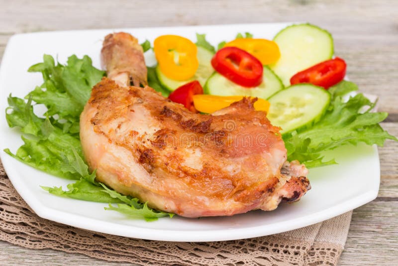 Muslo y verduras asados a la parrilla picantes del pollo en una placa blanca fotografía de archivo Muslo y verduras asados a la parrilla picantes del pollo en una placa blanca fotografía de archivo