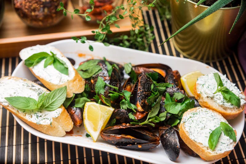 Mussels in tomato sauce with a slice of lemon and tapas with a spread of cottage cheese with basil royalty free stock photos Mussels in tomato sauce with a slice of lemon and tapas with a spread of cottage cheese with basil royalty free stock photos