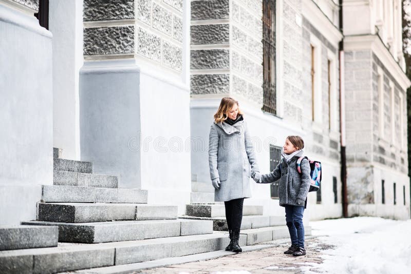 Mutter, die Tochter zur Schule bringt und sich vor dem Schulgebäude verabschiedet, um zu arbeiten. Konzept des Arbeitslebens stockfotos