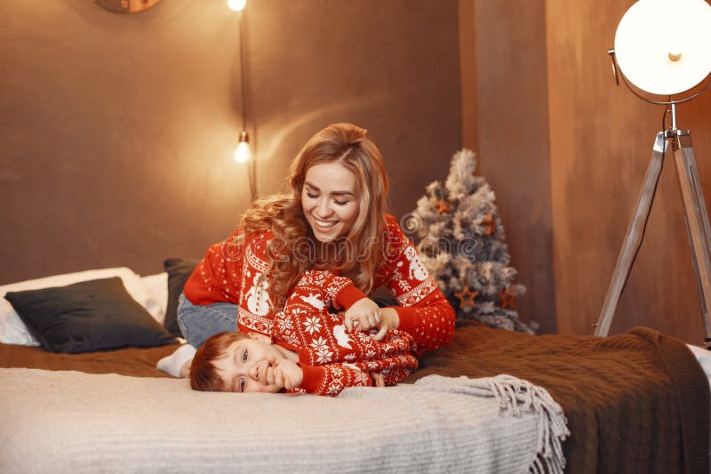 Mutter in einem roten Pullover mit süßem Sohn zu Hause stockfotos
