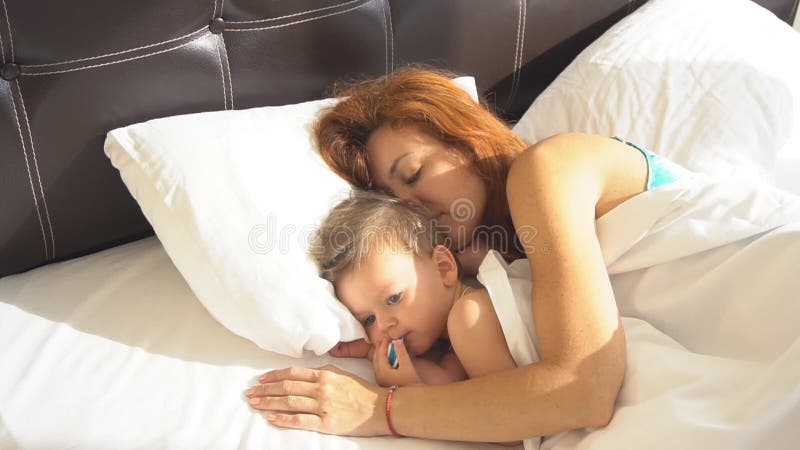 Mutter mit Sohnbaby wachte morgens auf dem Bett auf stock video