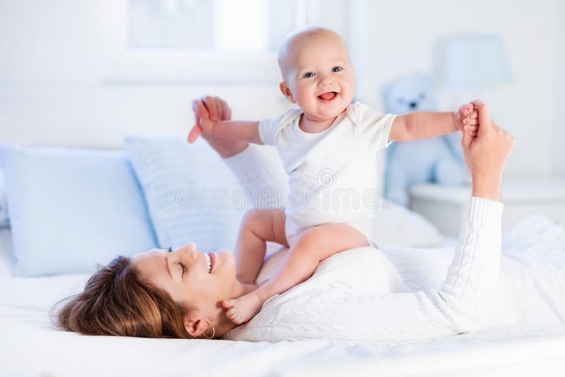 Mutter und Baby auf einem weißen Bett stockbild Mutter und Baby auf einem weißen Bett stockbild