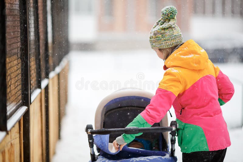 Mutter und Baby im Spaziergänger auf Weg, Wetter des verschneiten Winters Schneefälle, Blizzard, im Freien lizenzfreie stockbilder Mutter und Baby im Spaziergänger auf Weg, Wetter des verschneiten Winters Schneefälle, Blizzard, im Freien lizenzfreie stockbilder
