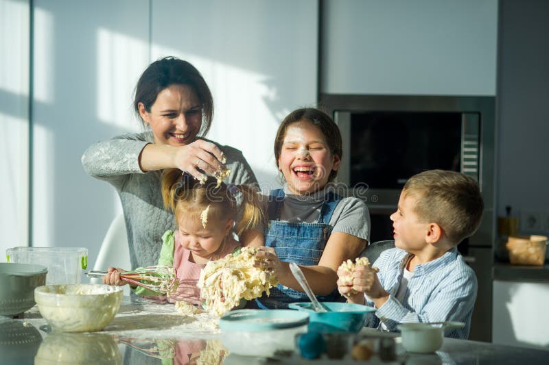 Mutter und drei Kinder bereiten etwas vom Teig vor stockfotos Mutter und drei Kinder bereiten etwas vom Teig vor stockfotos