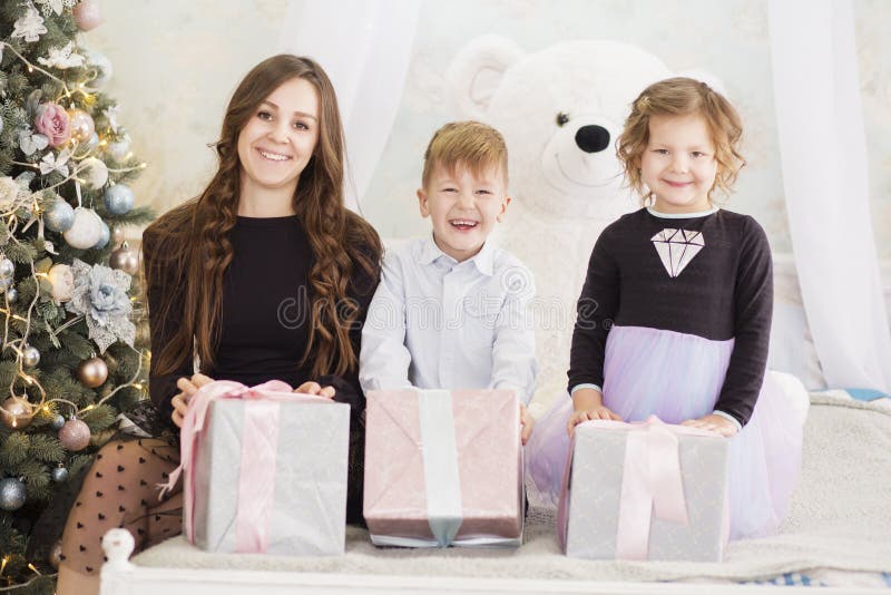 Mutter und ihre zwei kleinen Kinder mit Weihnachtsgeschenkboxen Familie auf Weihnachtsabend Mutter und Kleinkinder, die Weihnacht lizenzfreies stockfoto