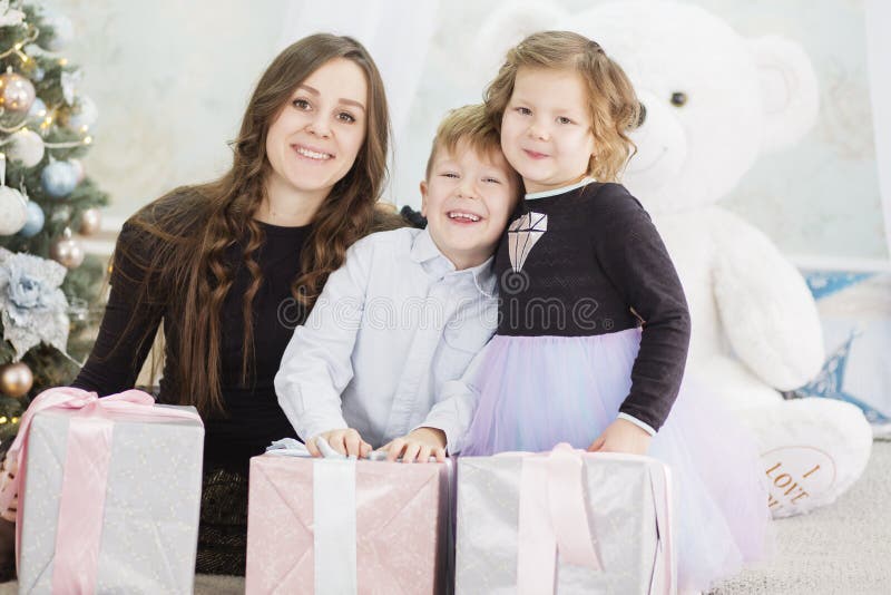 Mutter und ihre zwei kleinen Kinder mit Weihnachtsgeschenkboxen Familie auf Weihnachtsabend Mutter und Kleinkinder, die Weihnacht stockfotos