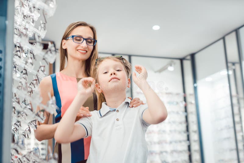 Mutter und Sohn beide, welche die Brillen angeboten im Optiker m?gen, kaufen stockbild Mutter und Sohn beide, welche die Brillen angeboten im Optiker m?gen, kaufen stockbild