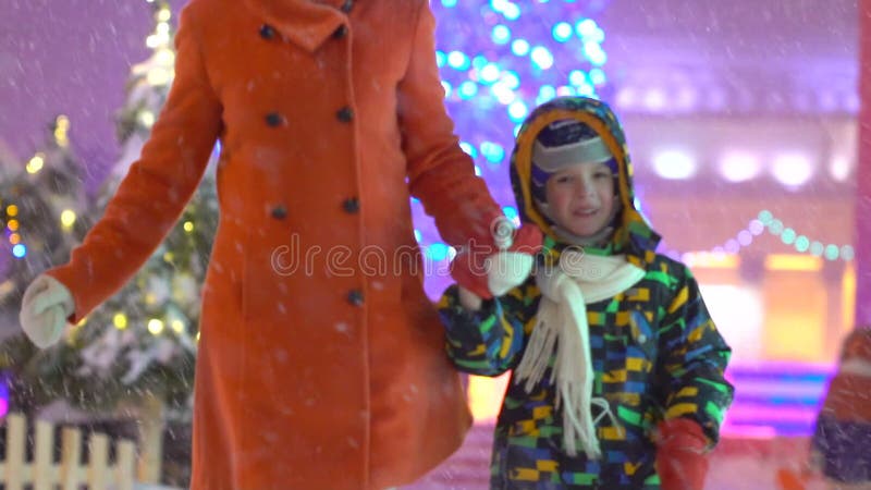 Mutter und Sohn, die Spaß und Laufhändchenhalten auf dem Hintergrund der Weihnachtsstraße haben Vektorversion in meinem Portefeui