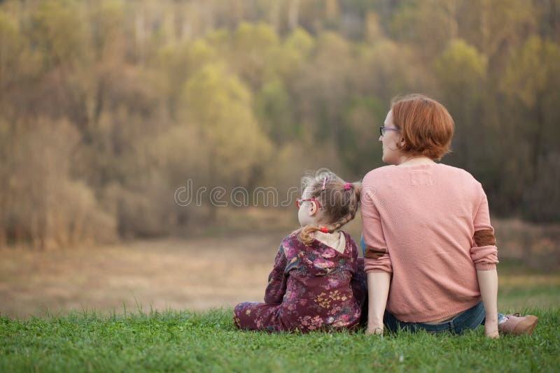 Mutter und Tochter in den Gläsern sitzen auf dem Gras und die Lücke auf lizenzfreie stockbilder