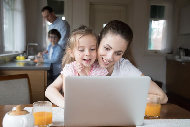 Mutter und Tochter, die Computer w? hrend Vater- und Sohnkochen spielen stockbild