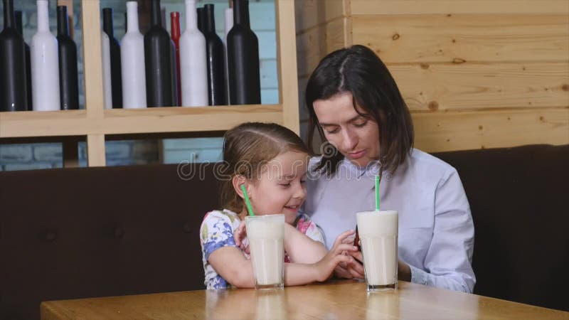 Mutter und Tochter, die einen Handy in einem Café verwendet