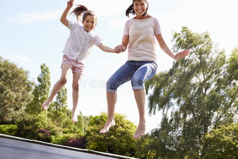 Mutter und Tochter, die zusammen auf Trampoline aufprallen lizenzfreie stockbilder Mutter und Tochter, die zusammen auf Trampoline aufprallen lizenzfreie stockbilder
