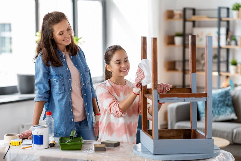 renovation, diy and home improvement concept - happy smiling mother and daughter cleaning old round wooden table surface with tissue. renovation, diy and home improvement concept - happy smiling mother and daughter cleaning old round wooden table surface with tissue