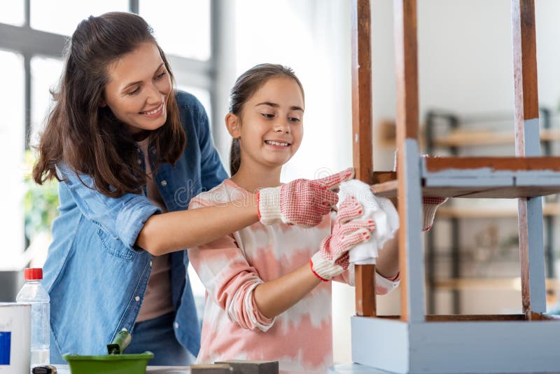 renovation, diy and home improvement concept - happy smiling mother and daughter cleaning old round wooden table surface with tissue. renovation, diy and home improvement concept - happy smiling mother and daughter cleaning old round wooden table surface with tissue