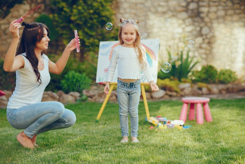 Mutter- und Tochterzeichnung. Schönheitsmutterfarbe mit ihrer kleinen Tochter Stilvolle Frauen, die das Bild mit wenigem Mädchen zeichnen Nettes Kind in einem weißen T-Shirt und in den Blue Jeans