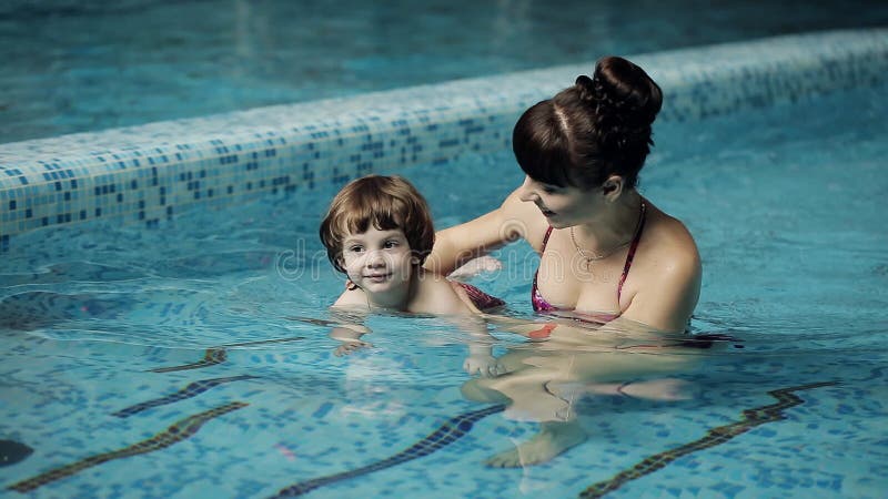 Mutter unterrichtet ein Kind, im Pool zu schwimmen