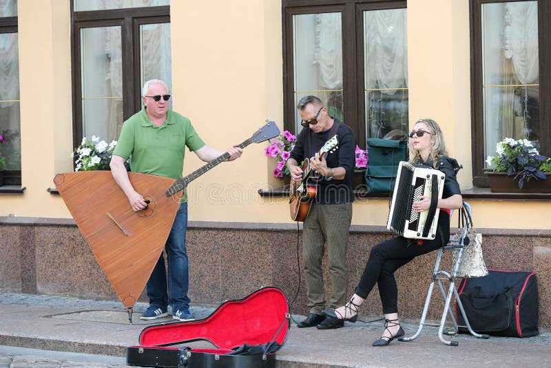 Muzikale triomensen op een oude Europese straat De band bestaat uit twee mensen en ??n meisje Mensen met dubbele baarzen en a stock afbeelding Muzikale triomensen op een oude Europese straat De band bestaat uit twee mensen en ??n meisje Mensen met dubbele baarzen en a stock afbeelding