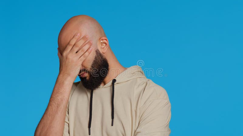 Muslim man suffering from serious migraine on camera, trying to rub temples to ease the pressure. Young middle eastern adult feeling unwell with painful headache, sick person. Camera 2. Muslim man suffering from serious migraine on camera, trying to rub temples to ease the pressure. Young middle eastern adult feeling unwell with painful headache, sick person. Camera 2.