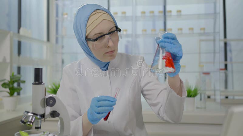 Muçulmano cientista em um laboratório moderno com frascos medindo nas mãos