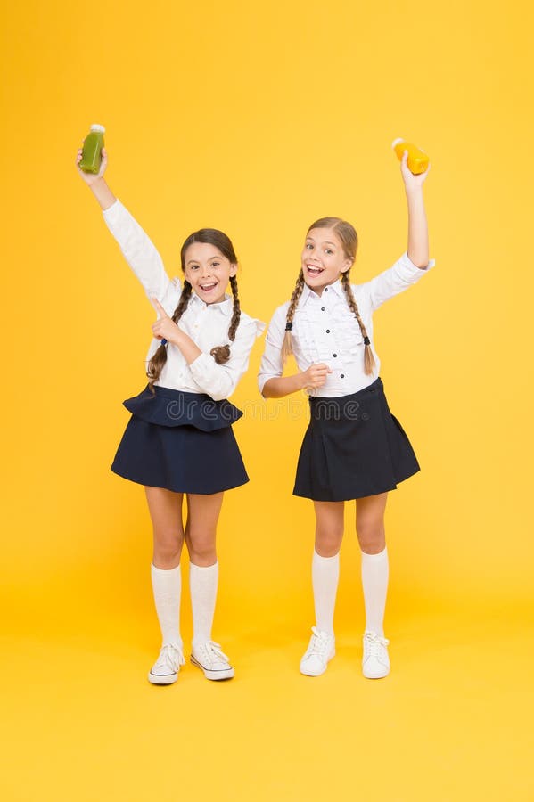 My favourite food. happy classmates in school uniform. back to school. little girls hold healthy juice or yoghurt. lunch royalty free stock images My favourite food. happy classmates in school uniform. back to school. little girls hold healthy juice or yoghurt. lunch royalty free stock images