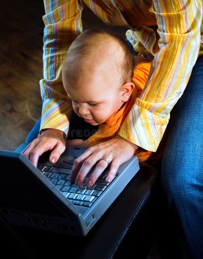 Una giovane madre è al lavoro su un computer notebook da casa, mentre lei si prende cura del suo bambino.