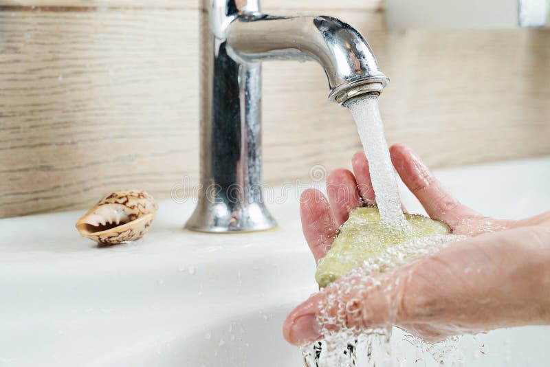 Soap in the hand of a man under a stream of water that flows from under the faucet. Soap in the hand of a man under a stream of water that flows from under the faucet