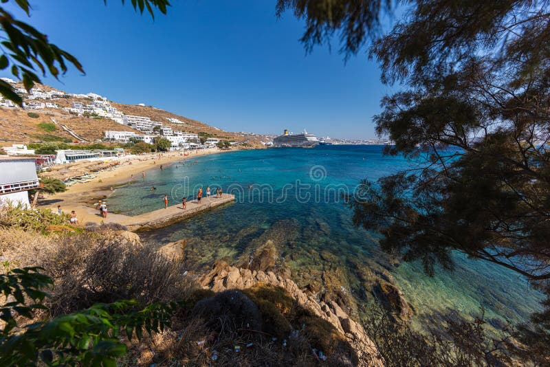 Mykonos, Greece - August 1, 2021: Panoramic wide angle view over the beach side of the island Mykonos. Mykonos is located in the cyclades archipelago in the Aegean Sea. Turquois water on sand beach. Mykonos, Greece - August 1, 2021: Panoramic wide angle view over the beach side of the island Mykonos. Mykonos is located in the cyclades archipelago in the Aegean Sea. Turquois water on sand beach
