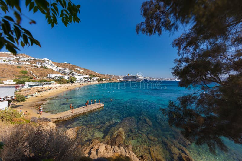 Mykonos, Greece - August 1, 2021: Panoramic wide angle view over the beach side of the island Mykonos. Mykonos is located in the cyclades archipelago in the Aegean Sea. Turquois water on sand beach. Mykonos, Greece - August 1, 2021: Panoramic wide angle view over the beach side of the island Mykonos. Mykonos is located in the cyclades archipelago in the Aegean Sea. Turquois water on sand beach