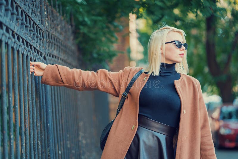 Mysteriöses stilvolles blondes Mädchen geht durch die europäische Metropole und hält den alten Zaun Porträt der jungen Frau herei lizenzfreie stockfotos Mysteriöses stilvolles blondes Mädchen geht durch die europäische Metropole und hält den alten Zaun Porträt der jungen Frau herei lizenzfreie stockfotos