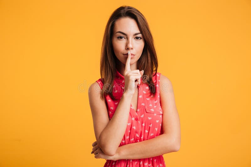 Mystery brunette woman in dress showing silence gesture