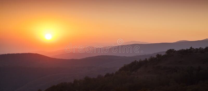 Golden sunset odlievanie farebných odtieňov cez misty mountains.