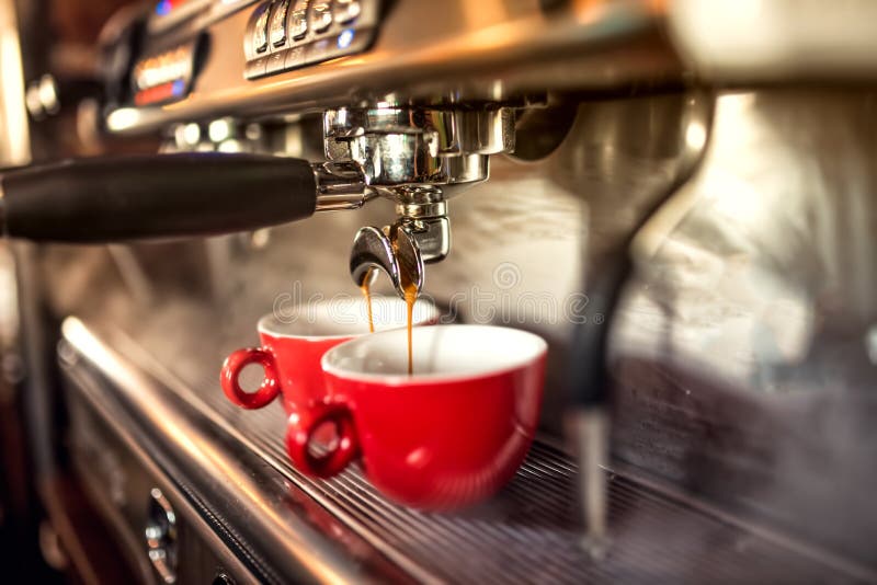 Máquina do café que prepara o café fresco e que derrama em copos vermelhos no restaurante, na barra ou no bar