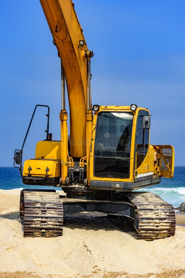 Máquina escavadora amarela sobre a areia fotografia de stock royalty free