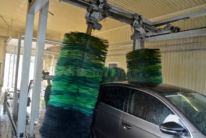 Auto is being washed by rotating brushes in an automatic car wash facility. Auto is being washed by rotating brushes in an automatic car wash facility