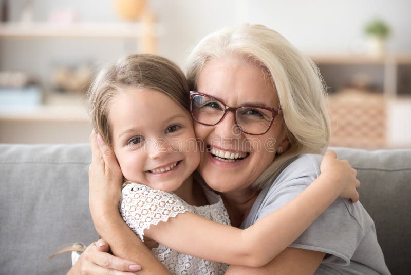 Más vieja abuela feliz que abraza a poca muchacha del nieto que mira a fotos de archivo libres de regalías