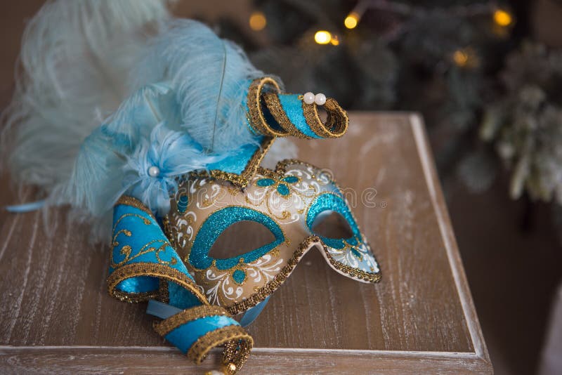 Máscara do carnaval do azul e do ouro que encontra-se em uma cadeira de madeira imagem de stock Máscara do carnaval do azul e do ouro que encontra-se em uma cadeira de madeira imagem de stock