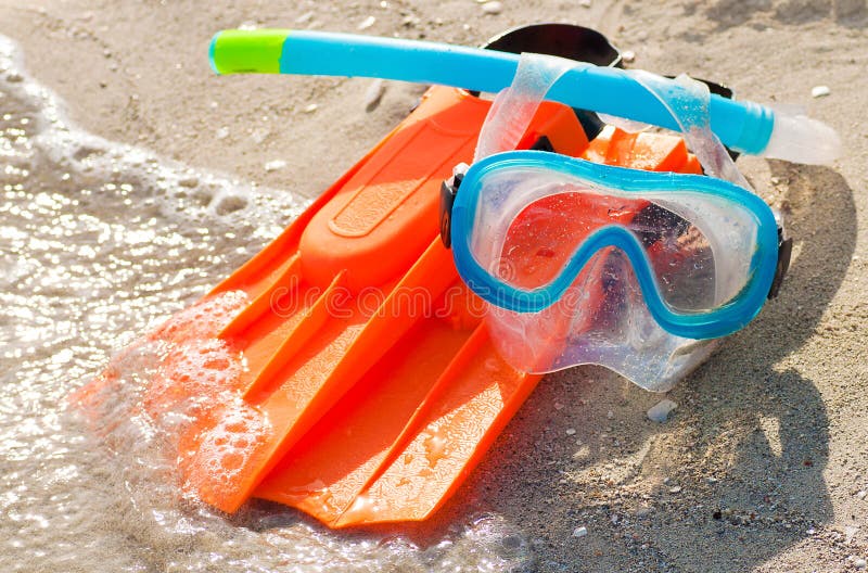 Brightly colored diving mask, snorkel and fins on a sandy beach. Brightly colored diving mask, snorkel and fins on a sandy beach