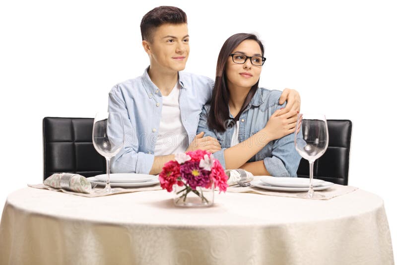 Mâle et femelle adolescents dans une étreinte se reposant à une table de restaurant regardant loin images libres de droits Mâle et femelle adolescents dans une étreinte se reposant à une table de restaurant regardant loin images libres de droits