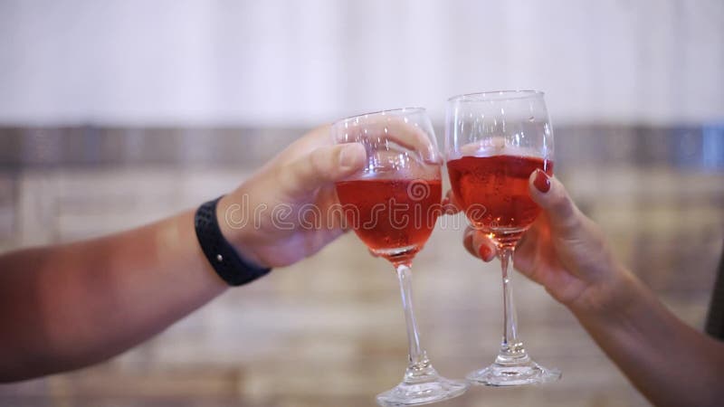 Mâle et mains femelles faisant tinter des verres avec la fin liquide rouge