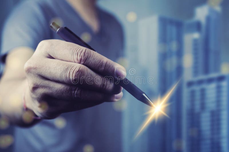 Mâna umană care ține un stilou cu lumină spumantă la nivelul pieptului. fundalul este format din zgârie-nori albaștri, ușor în afa royalty free stock photos