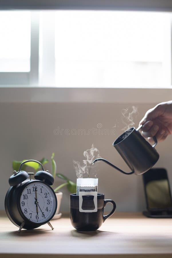 Mână care ține un ceainic turnând apă fierbinte într-o ceașcă de cafea dimineața lângă fereastră. royalty free stock photos