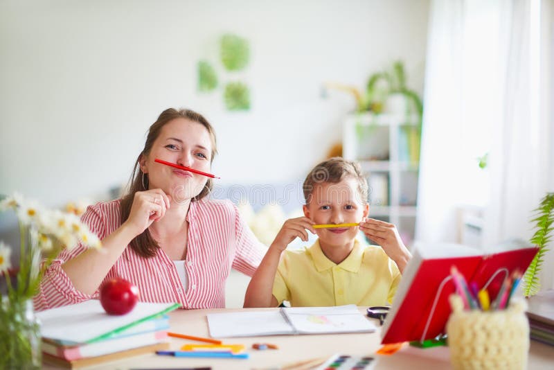 A mãe ajuda o filho a fazer lições educação de casa, lições da casa a mulher é contratada com a criança, verificações o trabalho imagens de stock royalty free A mãe ajuda o filho a fazer lições educação de casa, lições da casa a mulher é contratada com a criança, verificações o trabalho imagens de stock royalty free