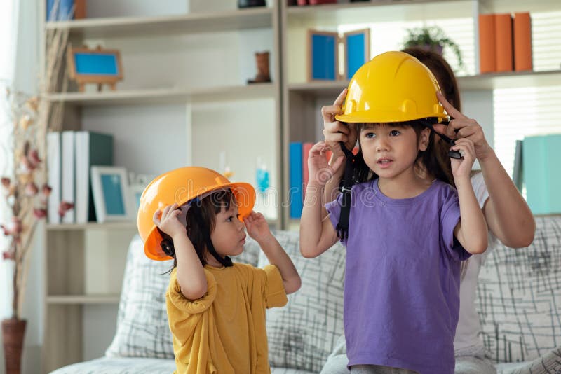 Mãe asiática a ajudar a filha a usar o conceito de educação e ocupação do capacete de engenheiro fotos de stock