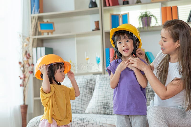 Mãe asiática a ajudar a filha a usar o conceito de educação e ocupação do capacete de engenheiro fotos de stock
