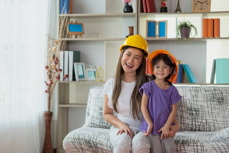 Mãe asiática e sua filha usando o conceito de educação e ocupação de capacete de engenheiro amarelo imagens de stock royalty free